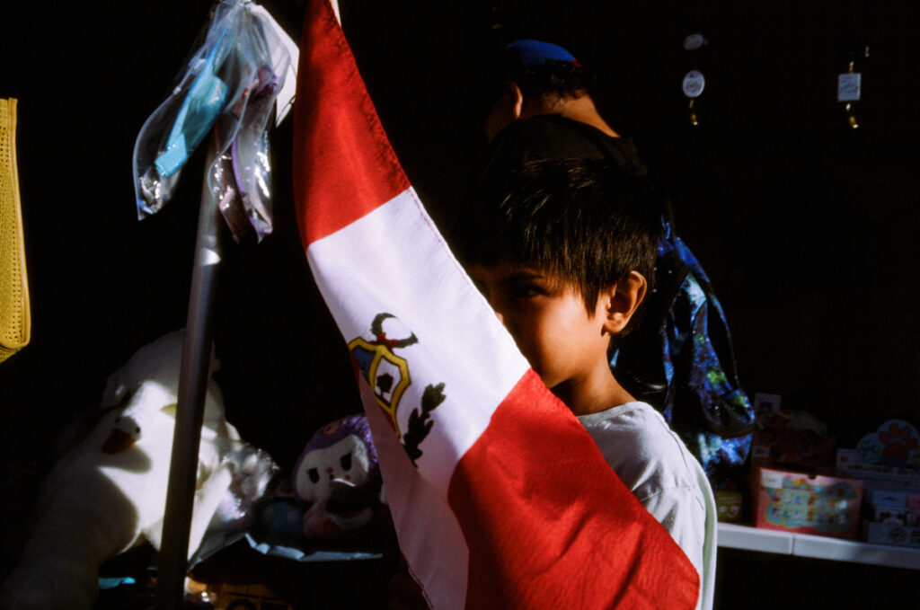 A young boy hiding behind a flag at the CNE, the Ex, the Canadian National Exhibition.