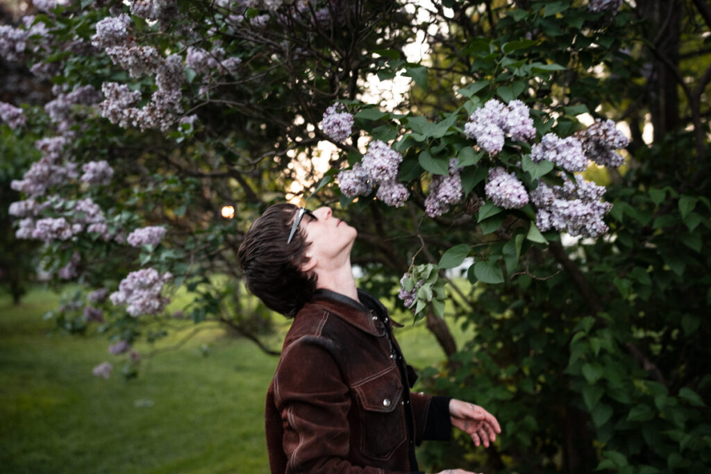 Sophie Blumenthal smelling a purple lilac bush in Trinity Bellwoods Park in Toronto