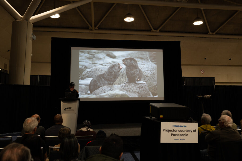 Christopher Dodds is on stage making a slide presentation at ProFusion Expo 2025 in Toronto.