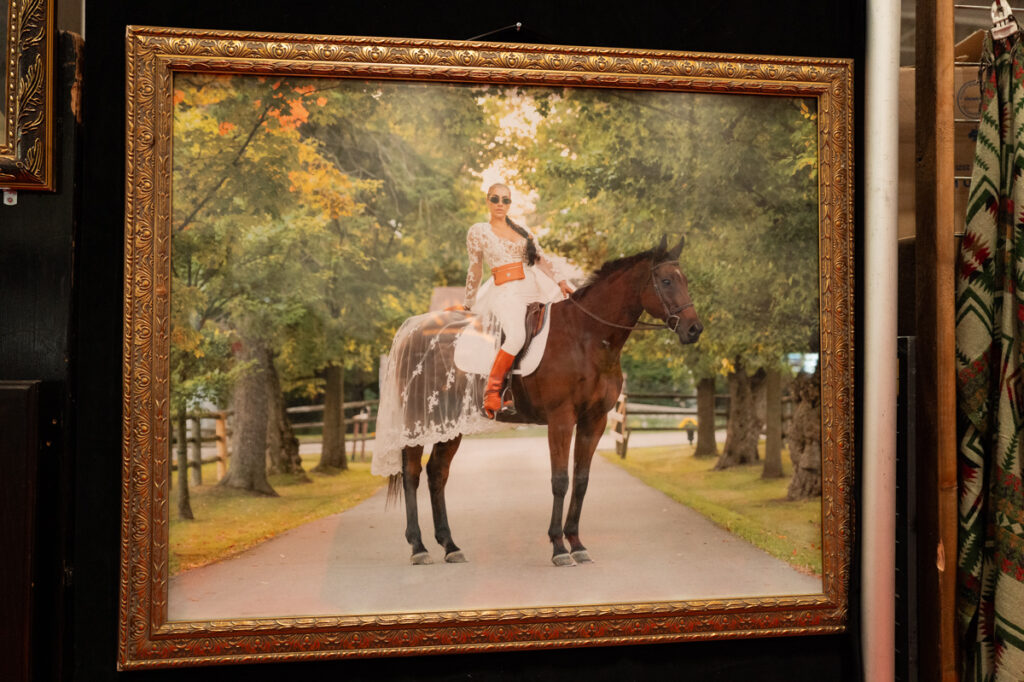 A photograph of a woman wearing sunglasses sitting atop a very tall horse at The Royal Agricultural Winter Fair in Toronto.