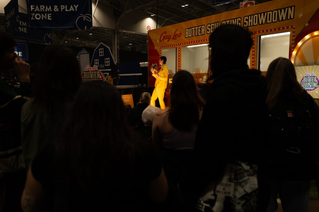 The host of the Gay Lea butter sculpting contest for kids in his butter-yellow suit onstage, performing for a crowd at The Royal Agricultural Winter Fair in Toronto.