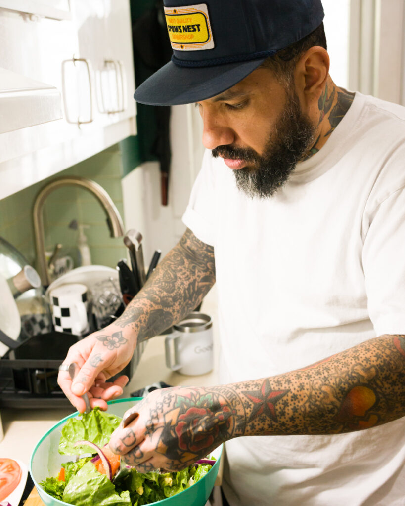 Chino is making a salad for lunch at Crows Nest Barbershop in Kensington Market in Toronto.